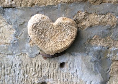 Petit coeur en pierre jaune accroché a un vieux mur