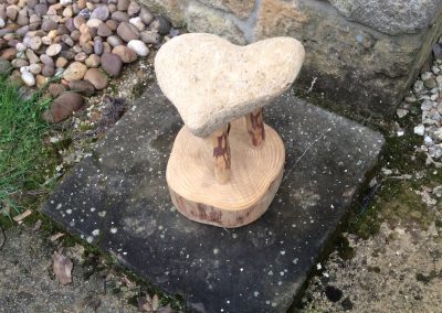 tabouret avec un tron4on de bois pour socle surmonter d'un coeur en pierre pour assise