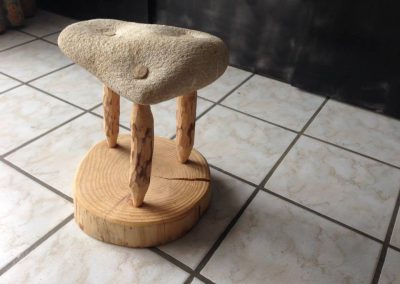 Tabouret fait d'un socle en bois surmonté de trois pieds en bois et pour assise une pierre taillée