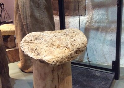 un tabouret avec pour assis une pierre avec un énorme pied en bois