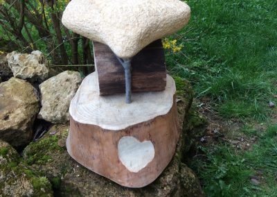 Tabouret fait de tronçon et rondin de bois avec pour assise une pierre en forme de selle de velo