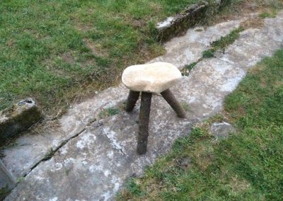 un tabouret avec une assise en pierre et trois pieds en bois