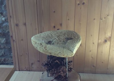 Un tabouret de pierre avec des pieds en fer planter dans un socle en bois